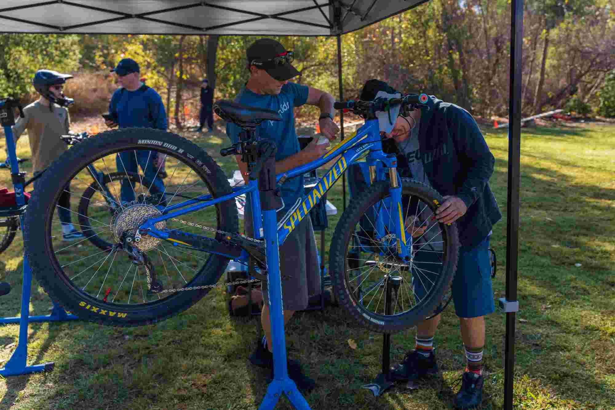 Mike Boon servicing a mountain bike on a repair stand at an ST Tuned outdoor suspension event
